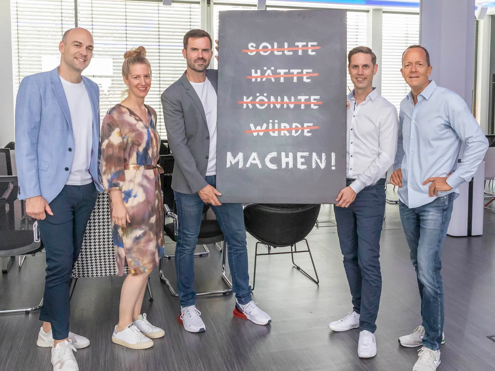 Team hält eine Motivations-Tafel hoch
